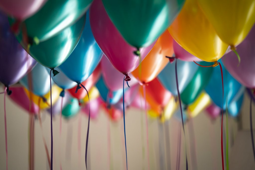 Colorful helium balloons floating against the ceiling.