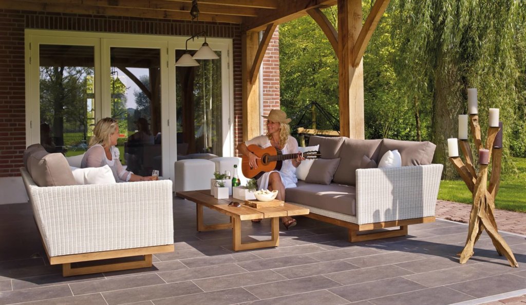 Two women sitting comfortably on furniture outdoors